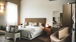 a bedroom with a large bed and a chair at Natiia Relais - Adults Only in Lazise