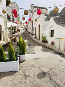 eine leere Straße mit Topfpflanzen und roten Dekorationen in der Unterkunft Jarubed in Alberobello