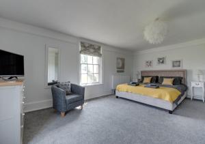um quarto com uma cama, uma cadeira e uma televisão em The Old Hall Farm House em Reydon