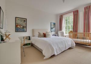 a bedroom with a large white bed and a crib at The Old Rectory in Haddiscoe