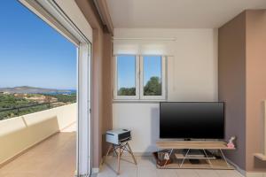 a living room with a flat screen tv and a balcony at Olive Tree Villa in Chania