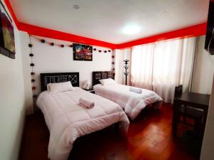2 camas en una habitación con paredes rojas en Qolmay Hostel Cusco en Cusco