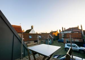 a table and chairs on a balcony with buildings at The Old Smokehouse in Southwold