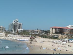 um grupo de pessoas numa praia com edifícios em Marina vaction rentals em Herzliya B