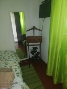 1 dormitorio con cama, escritorio y cortina verde en Casa da Praia Alfarim, en Sesimbra