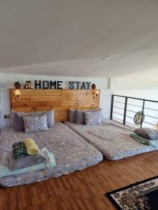 2 camas en una habitación con una señal de estancia en casa en la pared en Dicimulacion Staycation House en Angono
