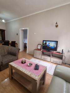 een woonkamer met een bank, een tafel en een tv bij Apartman Urošević in Osečina
