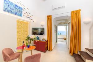 ein Wohnzimmer mit orangefarbenen Vorhängen sowie einem Tisch und Stühlen in der Unterkunft Suite Belvedere Capri Exclusive Rooms in Capri