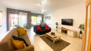 ein Wohnzimmer mit einem Sofa und einem TV in der Unterkunft Villa Jardins 2 by Sunny Deluxe in Albufeira