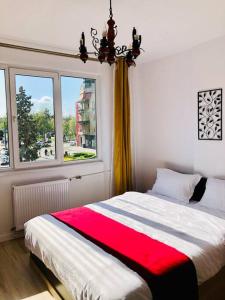 a bedroom with a bed with a red blanket and a window at Joy City Stay Victoriei 7G-9 in Timişoara