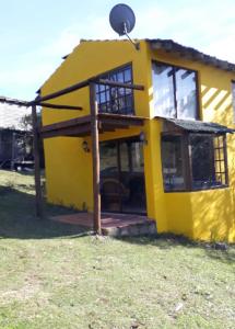una casa amarilla con un gran porche delantero en Peña de Horeb, en Villa Serrana