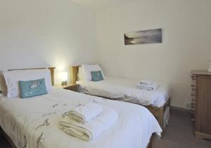 two beds in a room with towels on them at Tynewold in Southwold