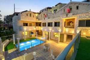 uma casa com uma piscina em frente em וילה ארמון מוראד - וילה מהממת הכוללת 8 סוויטות, בריכה מחוממת ומקורה, ג'קוזי וסאונה em ‘Ein el Asad