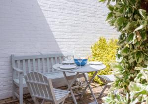 a table and chairs on a patio with a bench at Victoria Cottage in Woodbridge