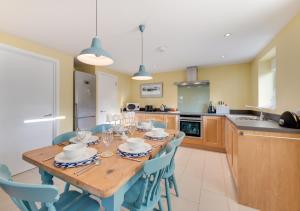 a kitchen with a wooden table and blue chairs at West Barn Cottage in Aldringham