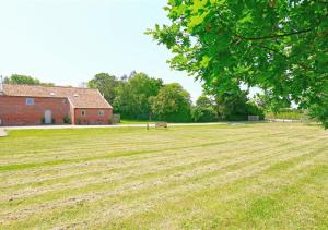 une grande pelouse avec une grange et un bâtiment dans l'établissement West Barn Cottage, à Aldringham