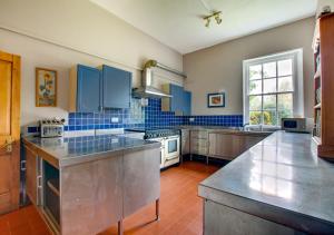 duża kuchnia z niebieskimi ścianami wyłożonymi kafelkami i urządzeniami ze stali nierdzewnej w obiekcie The Old Rectory w mieście Tattingstone