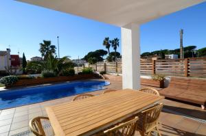 a patio with a wooden table and chairs and a pool at Ponent in L'Escala
