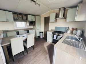 a kitchen with a sink and a table with chairs at Lets Host Hot Tub Holiday Home with Lake view in Patrington