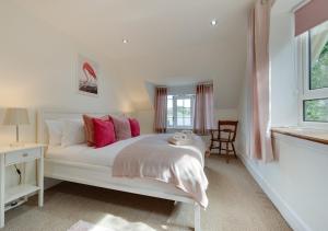 a bedroom with a large white bed with pink pillows at Tower Cottage in Walberswick