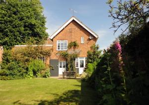 a large brick house with a lawn in front of it at Wing Cottage in Orford