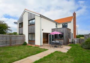 a house with a patio and a table with a pink umbrella at West View in Middleton