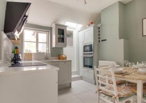 a kitchen with white cabinets and a table in it at Wren Cottage in Woodbridge
