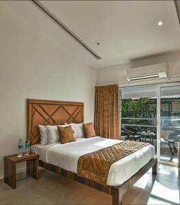 ein Schlafzimmer mit großem Bett und Balkon in der Unterkunft Meritas Countryside Resort Lonavala in Lonavla