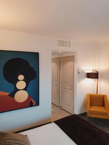 a bedroom with a painting on the wall and a chair at Patio De Violette in Uzès