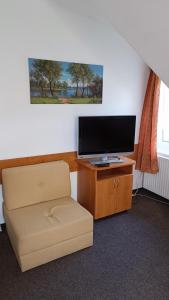 een woonkamer met een televisie en een stoel bij Motel Velký Rybník in Pelhřimov
