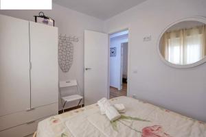 Cette chambre blanche comprend un lit et un miroir. dans l'établissement Casa Gardenia centro historico a 200m de la playa sólo familias, à Conil de la Frontera