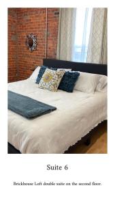 a bed with white sheets and blue pillows on it at Brickhouse Loft - a boutique hotel in Martinsville