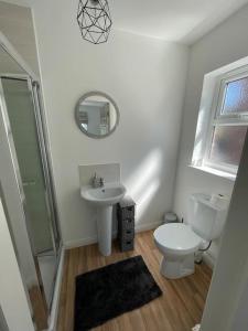 a white bathroom with a toilet and a sink at Cashel on the Coast, 3 bedroom holiday home, Ballycastle in Ballycastle