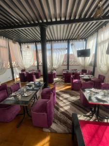 un restaurante con sillas moradas, mesas y ventanas en Majorel Perle Hôtel Riad Restaurant Picine & Spa, en Marrakech