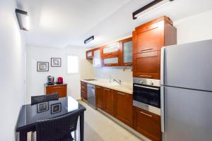 eine Küche mit Holzschränken und einem Kühlschrank aus Edelstahl in der Unterkunft Morning light near gordon beach by HolyGuest in Tel Aviv