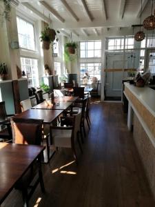 een restaurant met houten tafels, stoelen en ramen bij Bed & Brasserie Het Kosthuys in Sint Maartensdijk