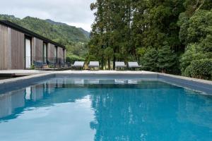 a swimming pool with blue water in front of a building at Landescape Furnas in Furnas