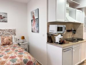 a small kitchen with a bed and a microwave at Estudios Costavigía Mazagón by Ramona in Mazagón