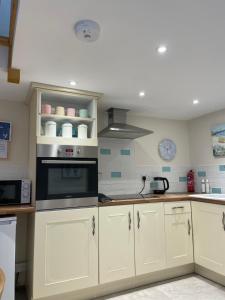 a kitchen with white cabinets and an oven at The Groom's Cottage in Towcester
