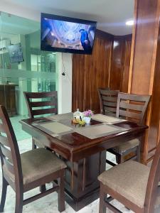 een houten tafel met stoelen en een televisie aan de muur bij Hotel El Mirador in Ciudad Valles