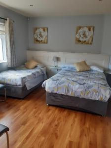 two beds in a room with wooden floors at Green Acres Guesthouse- Accommodation Only in Killarney