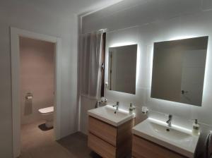a bathroom with two sinks and a mirror and a toilet at Apartamento Exclusivo San Marcos in Manzanares