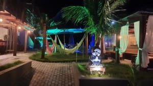 a resort with a hammock and palm trees at night at Pousada Mar e Paz in São Francisco do Sul