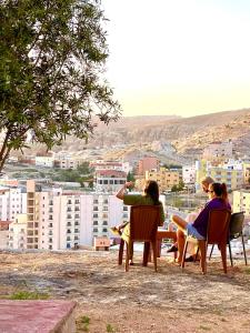 een groep mensen die aan een tafel zitten en naar een stad kijken bij RoadHouse - Petra in Wadi Musa