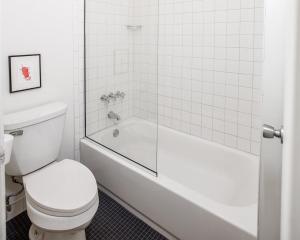 a white bathroom with a toilet and a bath tub at Trumbull and Porter - Detroit Downtown in Detroit