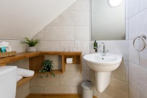 ein weißes Badezimmer mit Waschbecken und Spiegel in der Unterkunft The Hayloft in Chichester + 21 Fotos