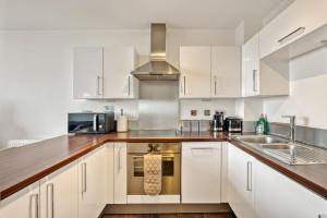una cucina con armadi bianchi e lavandino di Delightful Apartment Wandsworth a Londra