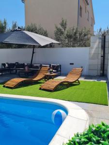 a swimming pool with two chairs and an umbrella at LuxVilla AURORA in Vodice