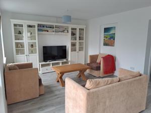 ein Wohnzimmer mit 2 Sofas und einem TV in der Unterkunft Deerpark Cottage, Inistioge, Kilkenny in Inistioge