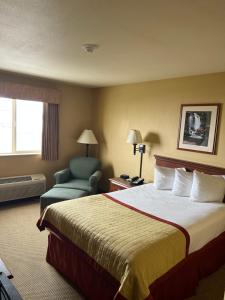 a hotel room with a bed and a chair at Pinedale Hotel & Suites in Pinedale